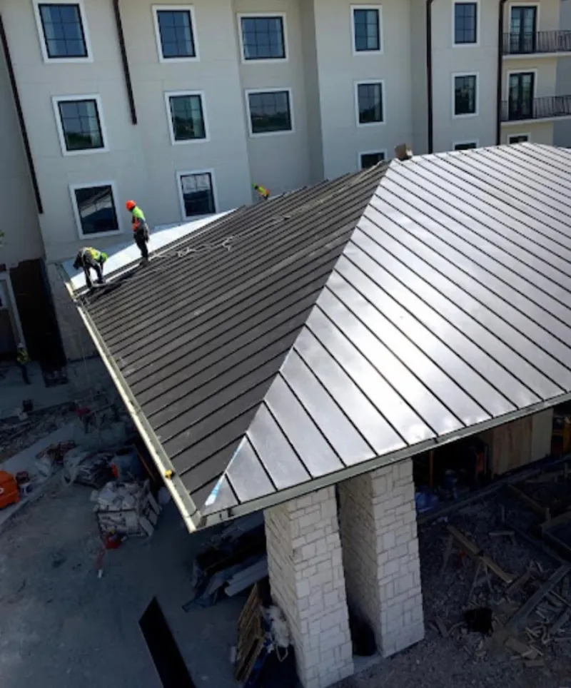 Crew installing standing seam metal roof panels on a commercial project in Northfield